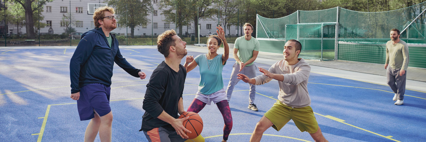 Freizeitsport auf dem Sportplatz, sechs Menschen spielen Basketball auf einem Sportplatz.