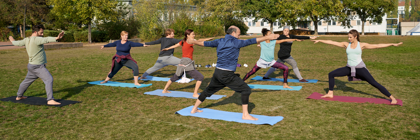 Eine Gruppe macht gemeinsam Yoga-Übungen im Park.