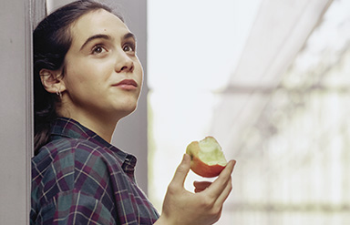 Eine junge Frau beißt in einen Apfel