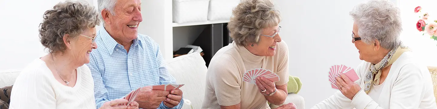 Gruppe von glücklichen älteren Männern und Frauen beim Kartenspiel 