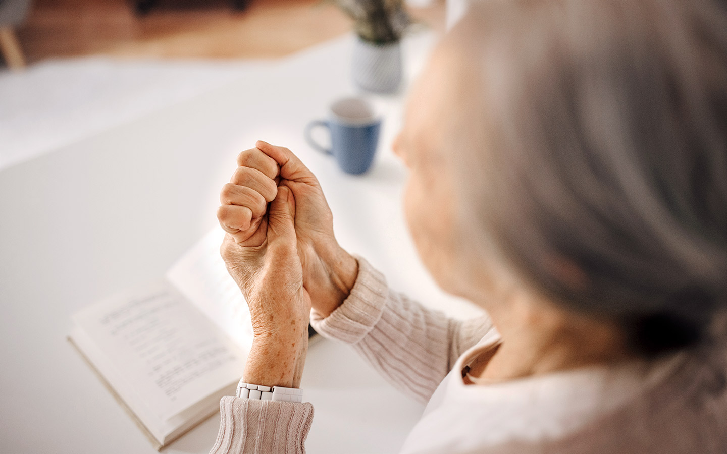 Foto: Ältere Frau fasst sich an das Handgelenk
