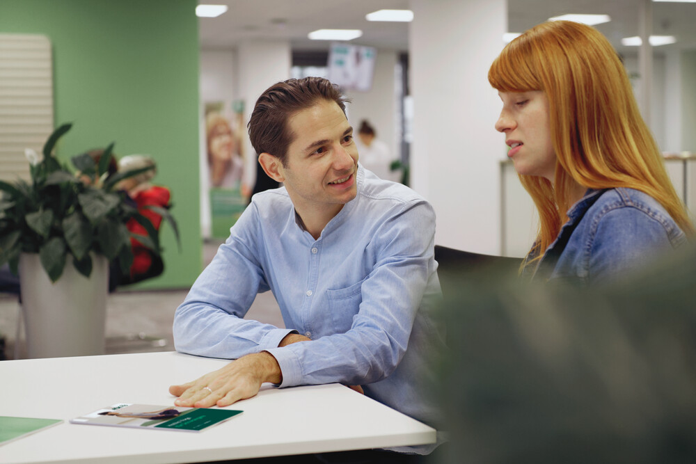 In einem AOK-KundenCenter sind ein Mann und eine Frau bei der Beratung zu sehen.