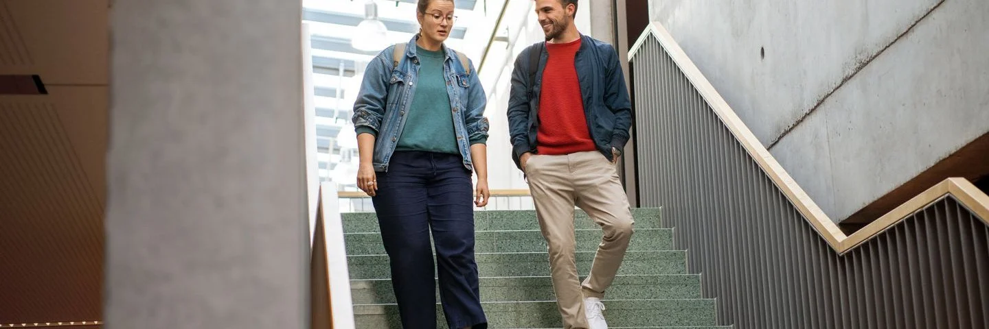 Eine Frau und ein Mann gehen eine Treppe hinunter und unterhalten sich dabei miteinander.