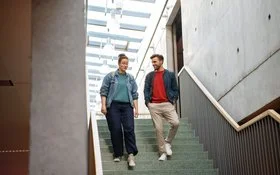 Eine Frau und ein Mann gehen eine Treppe hinunter und unterhalten sich dabei miteinander.