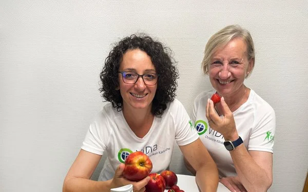 Zwei Frauen stehen vor einem Tisch, auf dem frisches Obst liegt.