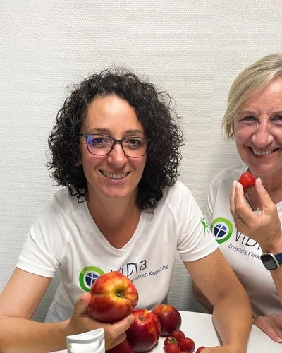 Zwei Frauen stehen vor einem Tisch, auf dem frisches Obst liegt.
