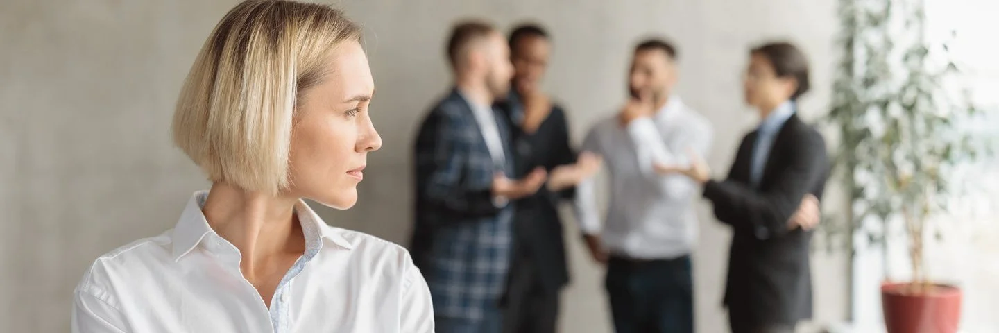 Eine Frau im Büro fühlt sich von einem Viererteam beobachtet.