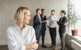 Eine Frau im Büro fühlt sich von einem Viererteam beobachtet.