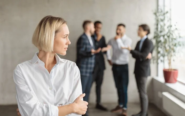 Eine Frau im Büro fühlt sich von einem Viererteam beobachtet.