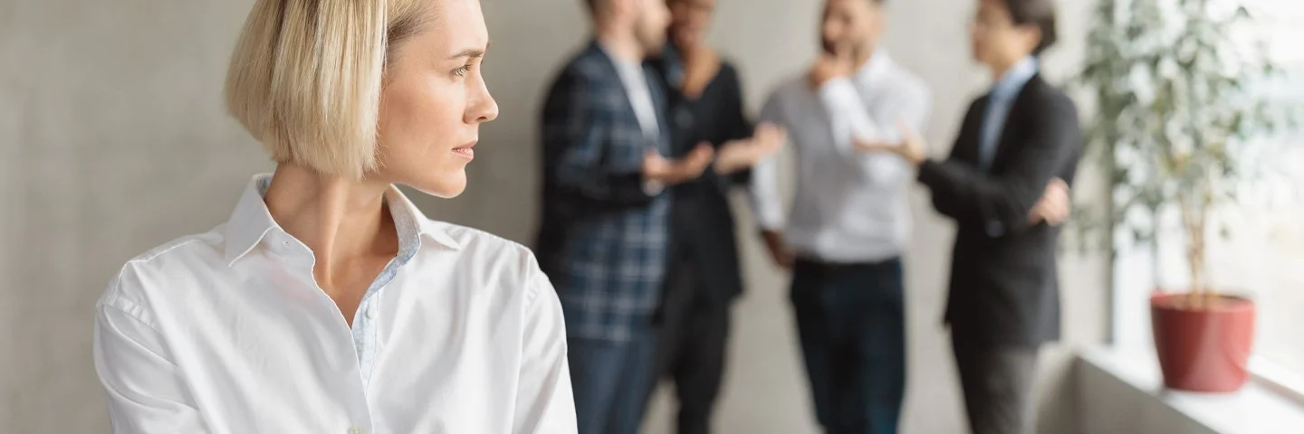 Eine Frau im Büro fühlt sich von einem Viererteam beobachtet.