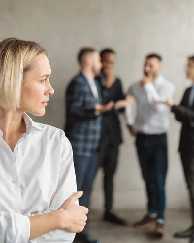 Eine Frau im Büro fühlt sich von einem Viererteam beobachtet.