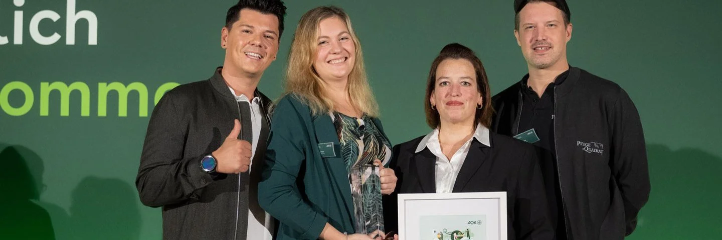 Zwei Männer und zwei Frauen präsentieren eine gerahmte Urkunde.