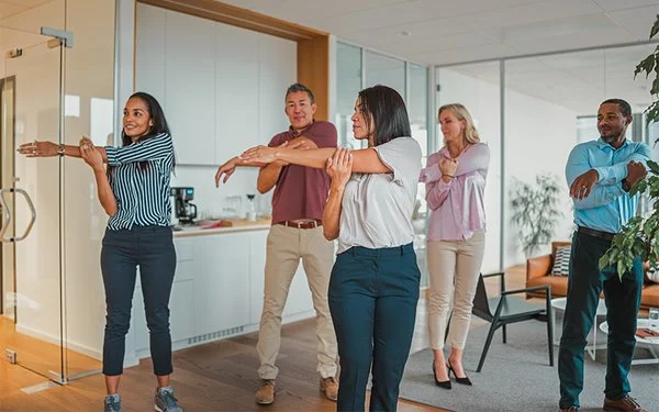 Gruppe von Mitarbeitenden bei einer aktiven Bewegungspause im Büro.