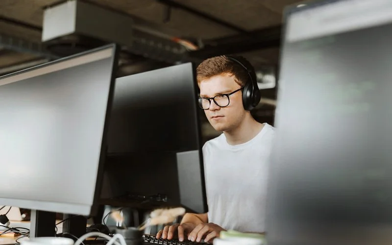 Ein junger Mann mit Kopfhörern am Laptop.