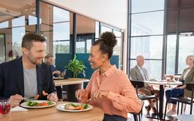 Ein Mann und eine Frau sitzen in einer Kantine am Tisch  und essen