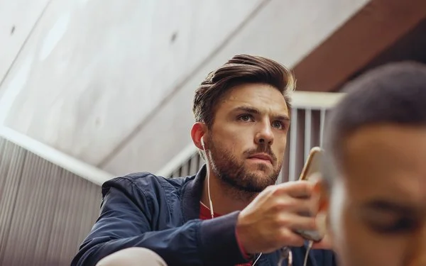Ein Mann schaut nachdenklich auf sein Smartphone.