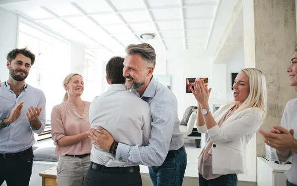 Zwei Männer umarmen sich im Büro