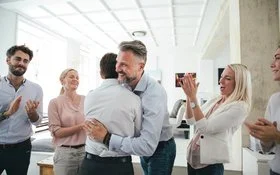 Zwei Männer umarmen sich im Büro