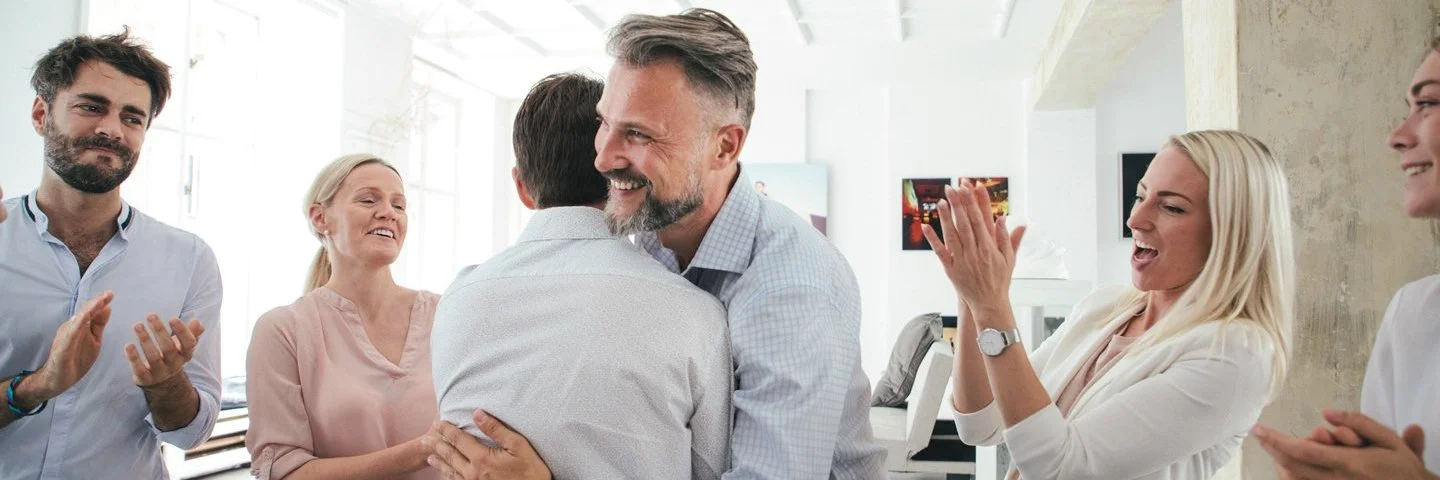 Zwei Männer umarmen sich im Büro