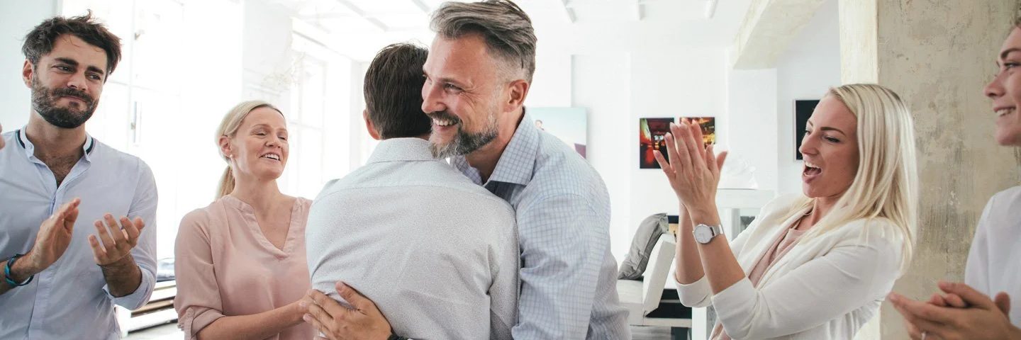 Zwei Männer umarmen sich im Büro