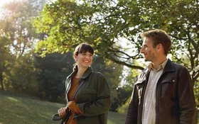 Eine Frau und eine Mann gehen gemeinsam spazieren und lächeln sich an.
