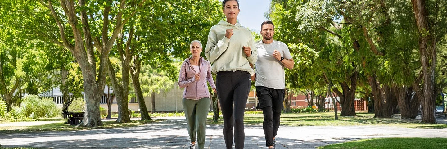 Zwei Frauen und ein Mann joggen gemeinsam im Park.