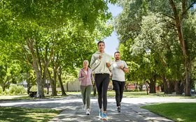 Zwei Frauen und ein Mann joggen gemeinsam im Park.