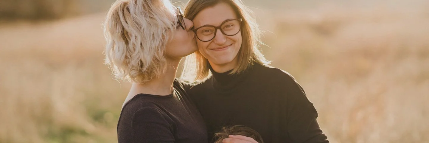 Ein Frauenpaar steht mit einem Kind auf einer Weide.