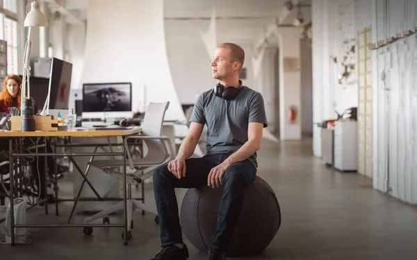 Ein Mann in einem Büro auf einem Sitzball