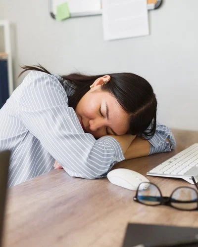 Mitarbeiterin ruht kurz am Arbeitsplatz – Symbolbild für Erholung und gesunden Schlaf im Arbeitsalltag