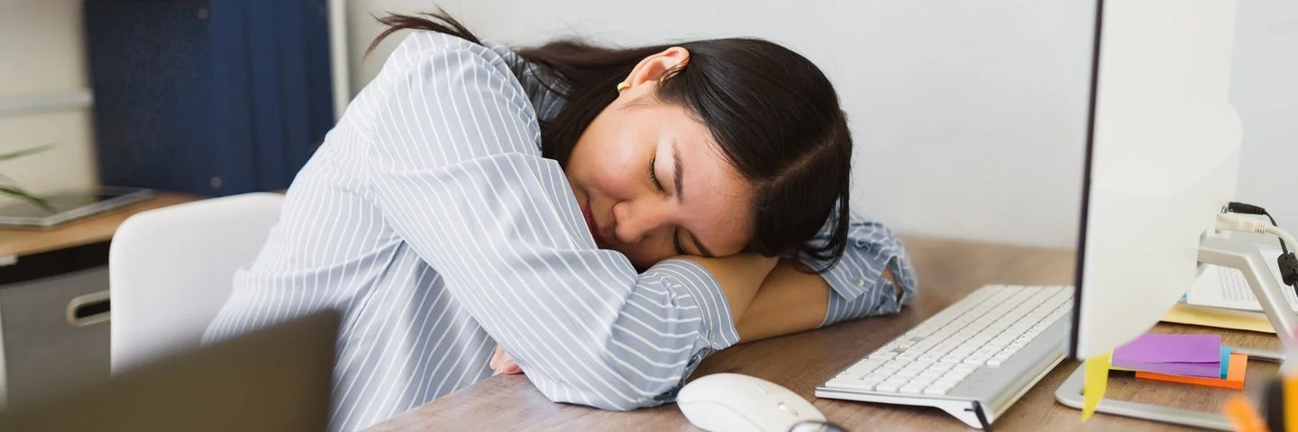 Mitarbeiterin ruht kurz am Arbeitsplatz – Symbolbild für Erholung und gesunden Schlaf im Arbeitsalltag