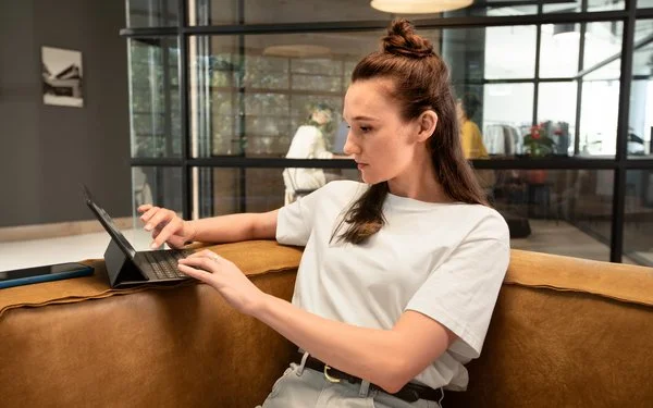 Eine Frau arbeitet konzentriert am Laptop in einem offenen Coworking-Space.