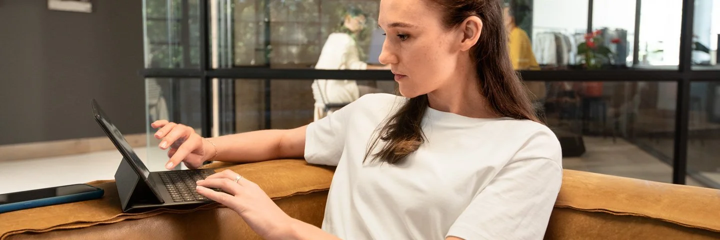 Eine Frau arbeitet konzentriert am Laptop in einem offenen Coworking-Space.