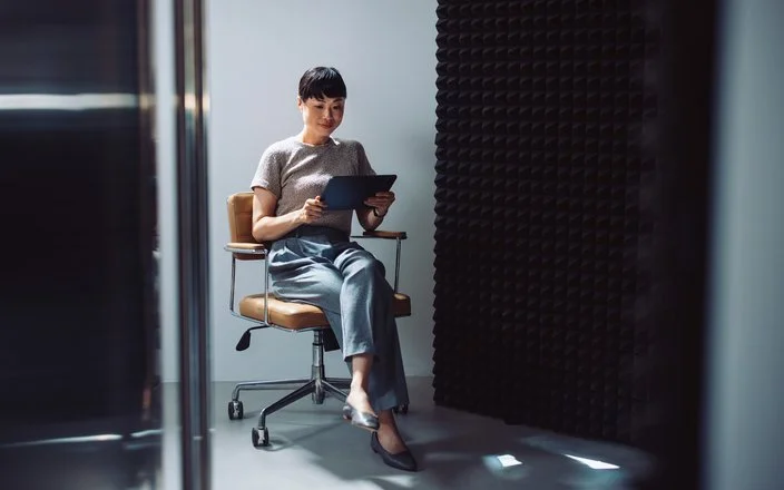 Frau auf Bürodrehstuhl mit digitalem Gerät