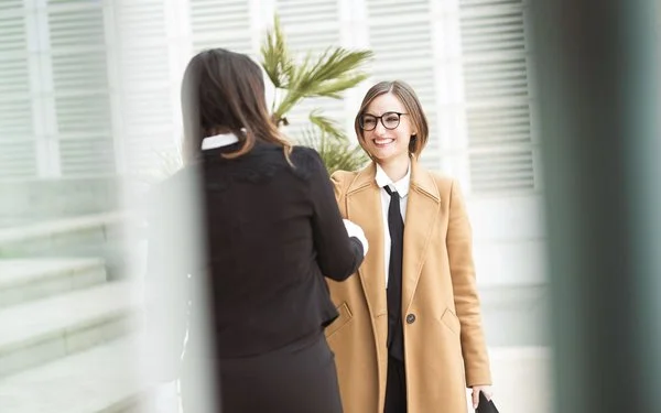 Zwei Frauen begrüßen sich mit einem Händedruck