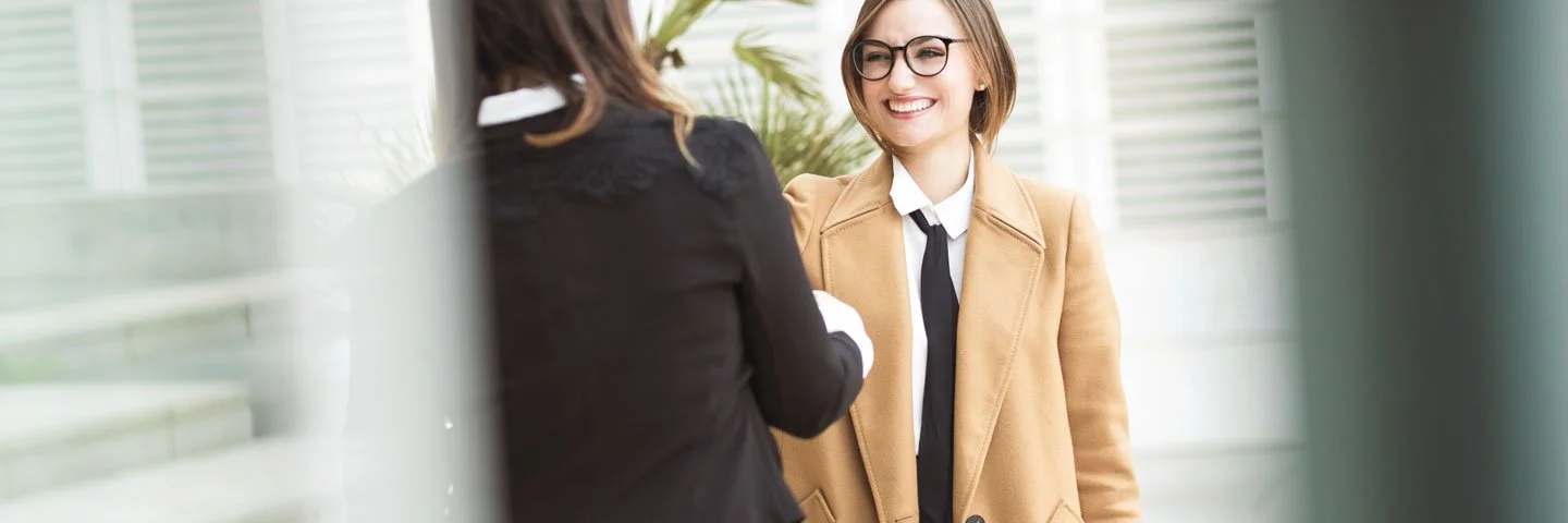 Zwei Frauen begrüßen sich mit einem Händedruck