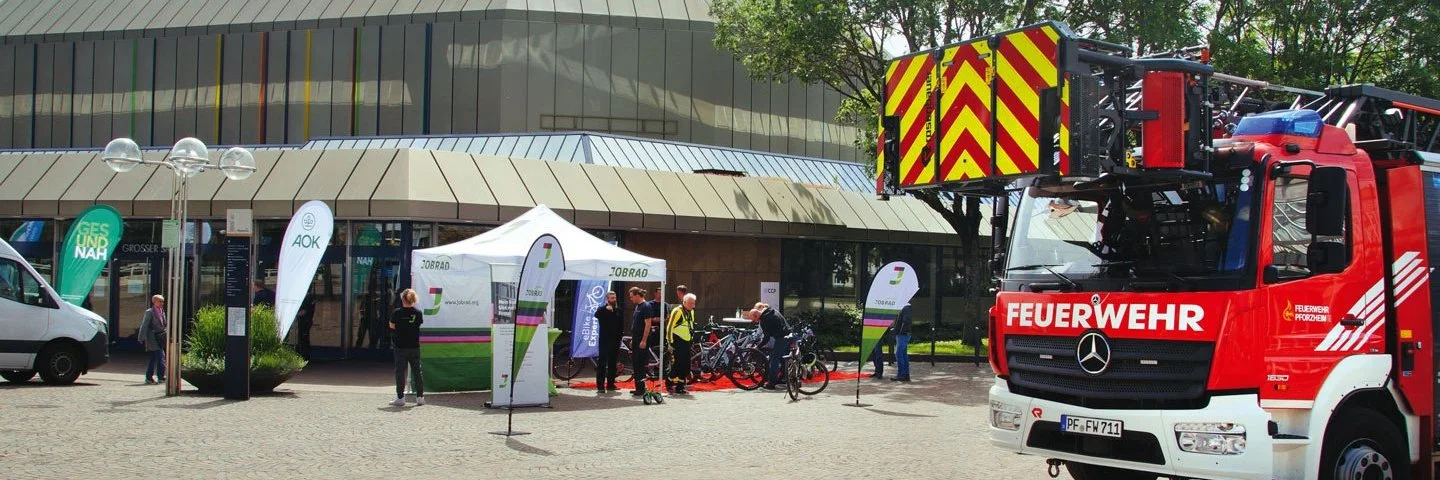 Ein Feuerwehrauto und ein AOK-Stand vor einem Gebäude