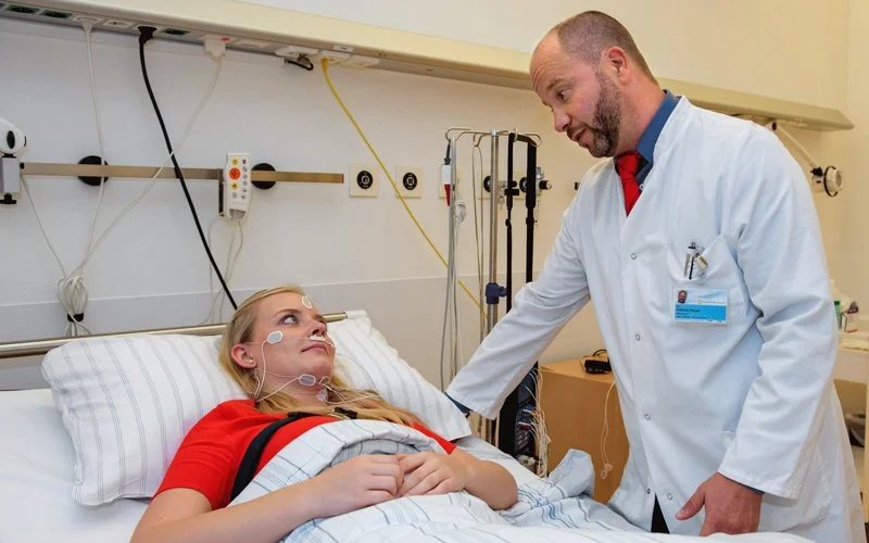 Dr. Matthias Berger im Gespräch mit einer Patientin, die im Bett liegt.