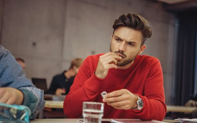 Ein Mann am Schreibtisch nimmt eine Tablette ein.