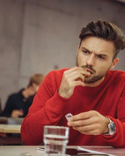 Ein Mann am Schreibtisch nimmt eine Tablette ein.