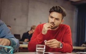 Ein Mann am Schreibtisch nimmt eine Tablette ein.