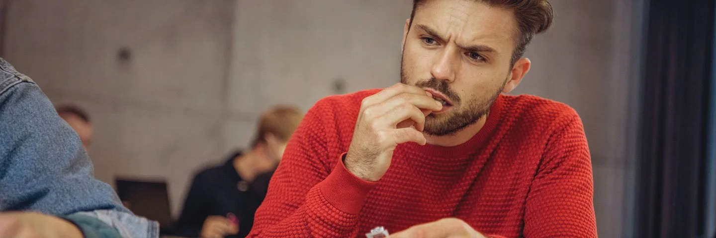 Ein Mann am Schreibtisch nimmt eine Tablette ein.