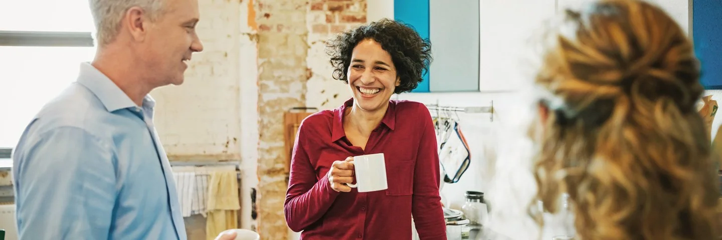 Drei Menschen stehen in einer Kaffeeküche und unterhalten sich.