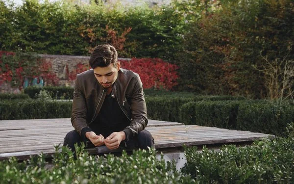 Ein Mann sitzt auf einem Steg und blickt nach unten.