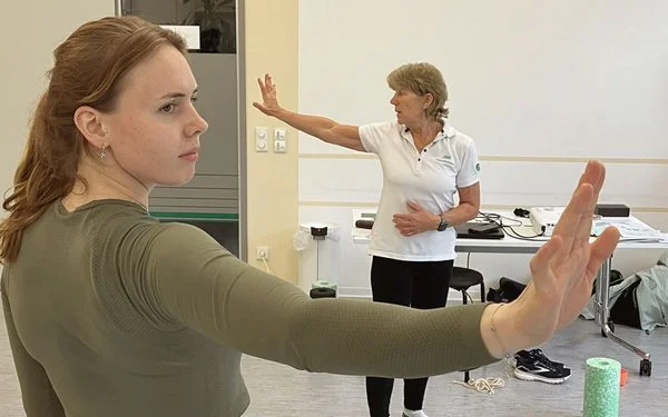 Zwei Frauen machen Dehnübungen im Stehen.