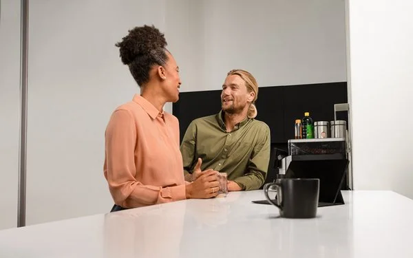 Zwei Personen stehen in der Kaffeeküche und unterhalten sich
