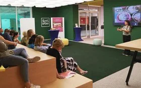Eine Menschengruppe sitzt in einem Konferenzraum und hört einem Vortrag zu 