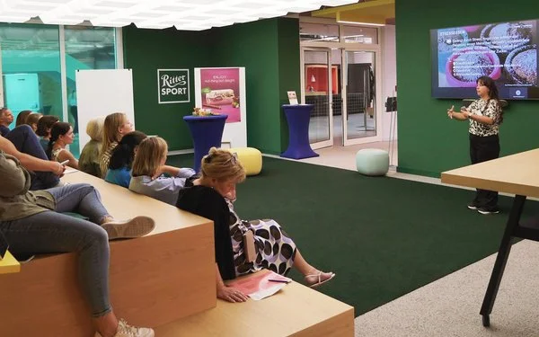 Eine Menschengruppe sitzt in einem Konferenzraum und hört einem Vortrag zu 