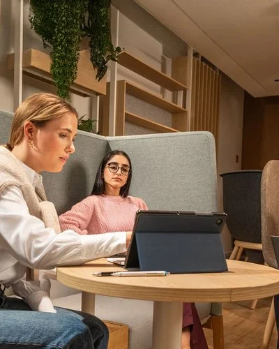 Drei Auszubildende sitzen vor Table-PCs an einem Besprechungstisch