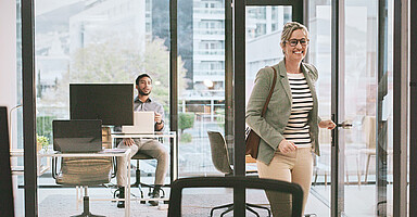 Grenzmanagement: Eine Frau verlässt gut gelaunt ein Büro. Grenzmanagement: Eine Frau verlässt gut gelaunt ein Büro.